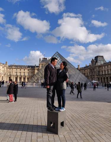Couple posing in front of the iconic Louvre Pyramid.