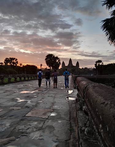 Group of people walking towards temples at sunset.