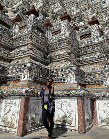 Woman posing in front of an intricately decorated pagoda.