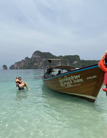 Couple enjoying a day by the beach with a traditional boat.