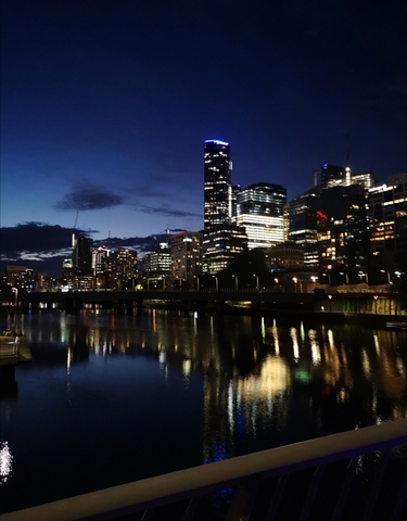 Night cityscape with modern skyline reflecting on water.