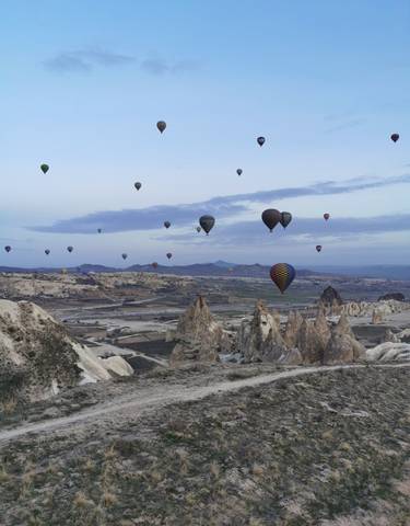 Hot air balloons floating over the rock formations in Cappadocia, Turkey.