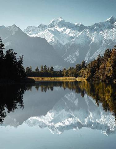 Serene landscape of a lake surrounded by mountains reflected on the water.