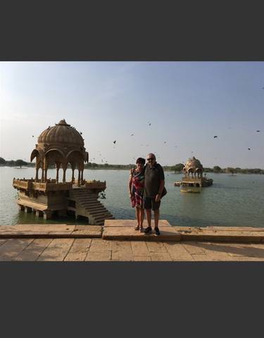Couple standing in front of a pavilion on a lake.