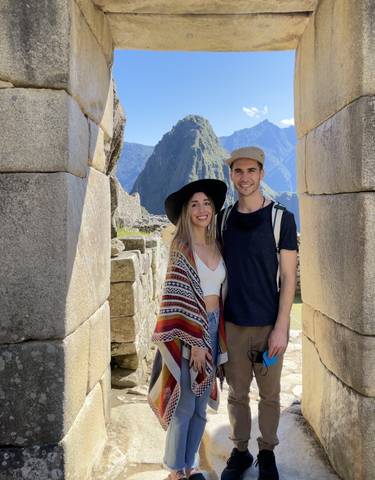 Two people posing in front of Machu Picchu with mountains in the background.