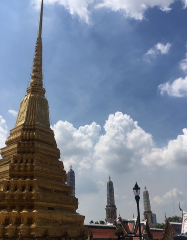 Golden stupa against a blue sky with clouds.