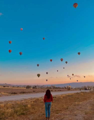 Hot air balloons floating over rocky landscape at sunrise.
