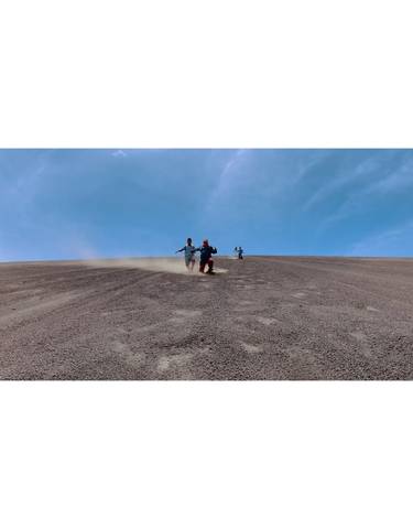 People gliding down a sandy hill.