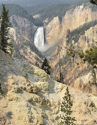Scenic view of a waterfall in a canyon with trees framing the scene.