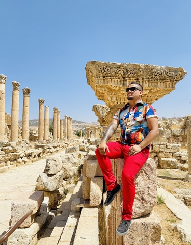 A man posing among ancient Roman ruins.