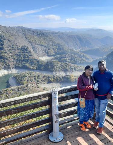 Couple at a scenic viewpoint overlooking a river.
