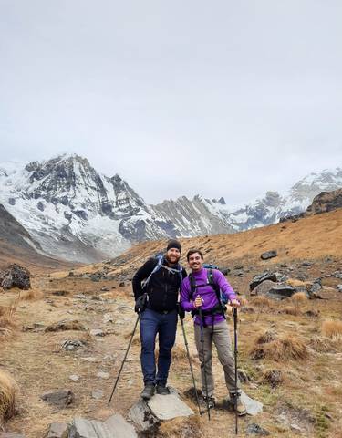 Two hikers posing in front of snow-covered mountains.
