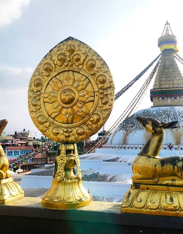 Golden religious symbols with a large stupa in the background.