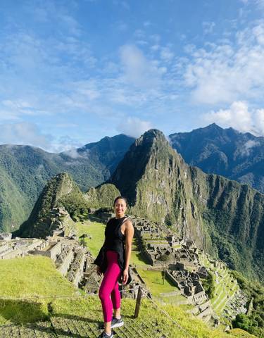 Person standing in front of Machu Picchu ruins with mountains in the background.