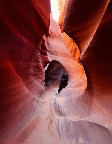 Person standing in a narrow red rock canyon.