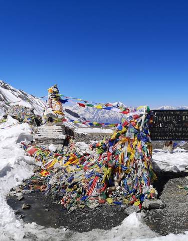 A pass with prayer flags and snowy mountain peaks.