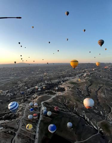 Numerous hot air balloons over Cappadocia landscape at sunrise.