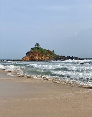 A rocky island with waves crashing on the shore.