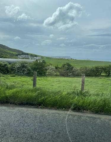 Green countryside with the ocean in the distance.