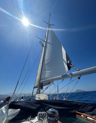 Sailboat with a partially unfurled sail under a clear blue sky.