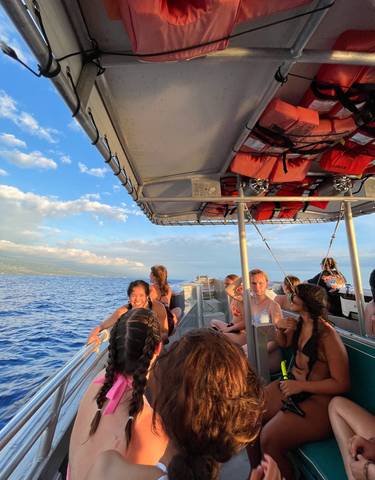 People on a boat enjoying a sunny day at sea with coast in the background.