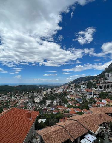 Panoramic view of a city with mountains and a partly cloudy sky.