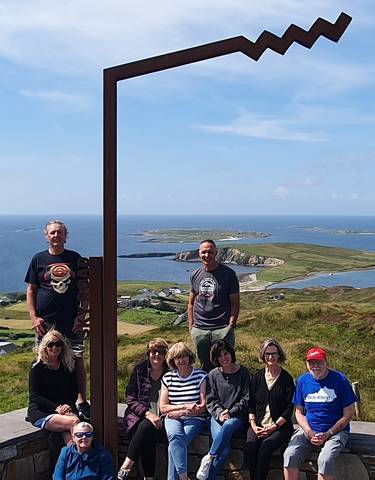 Two people standing at a scenic viewpoint with sea and islands.