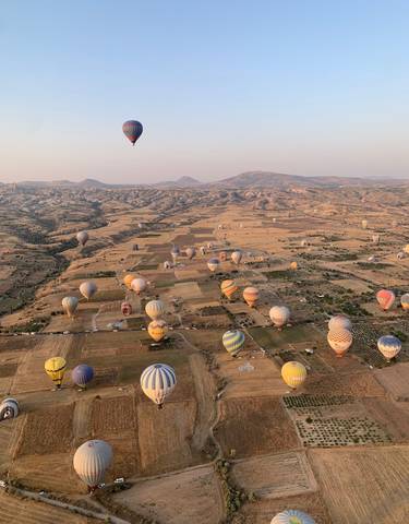 Hot air balloons over a wide landscape during sunrise.