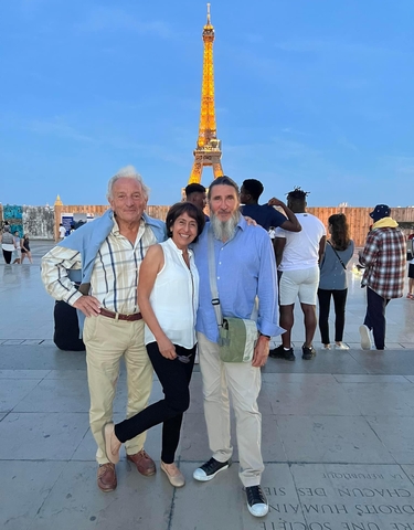 Three people posing in front of a famous landmark with a tower in the background.