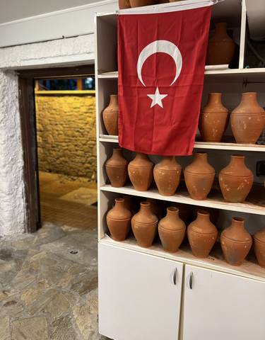 A display of clay pots with a Turkish flag in a shop.