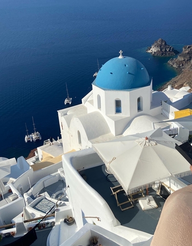 White and blue domed buildings overlooking a deep blue sea.