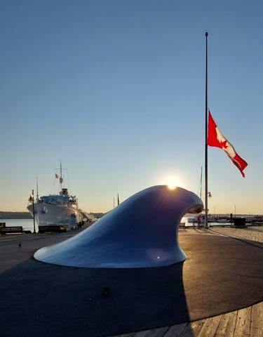 Ship and Canadian flag on a waterfront during sunset.