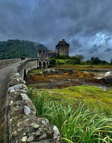 Iconic medieval castle with a stone bridge over a scenic landscape.