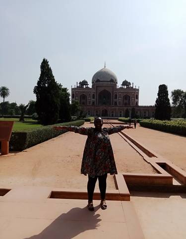 Person posing in front of a historic building with domes.
