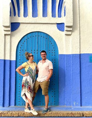 Two people in front of a blue arched door.