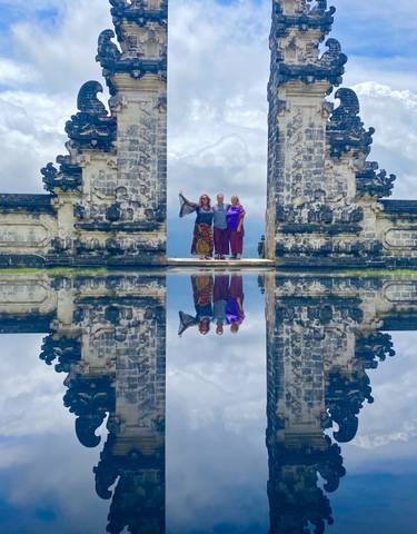 People posing in front of a Balinese gate with reflection.