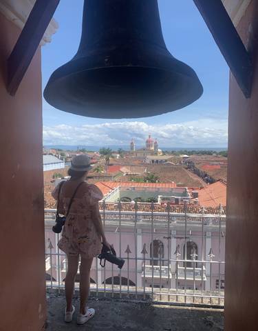 A person under an archway looking out at a city view with a colorful cathedral.
