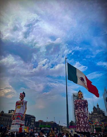 Large Mexican flag waving against a blue sky.