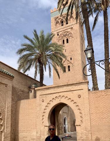 Tall stone mosque minaret surrounded by palm trees.