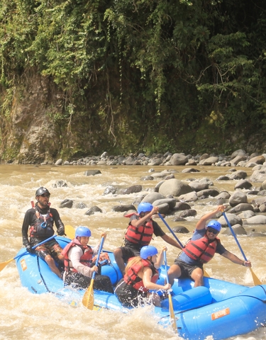 Group of people whitewater rafting on a rocky river.