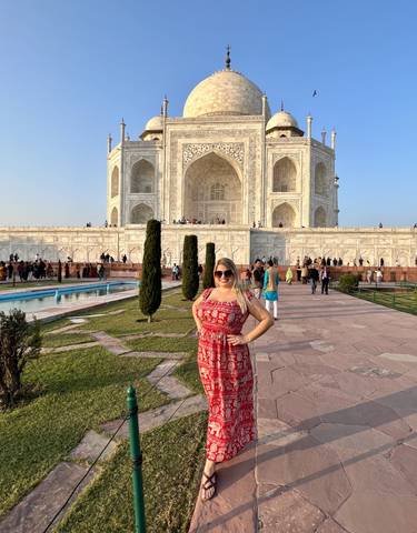 Woman happily posing in front of the majestic Taj Mahal.