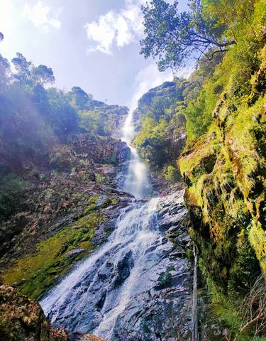 Tall waterfall in a rocky landscape.