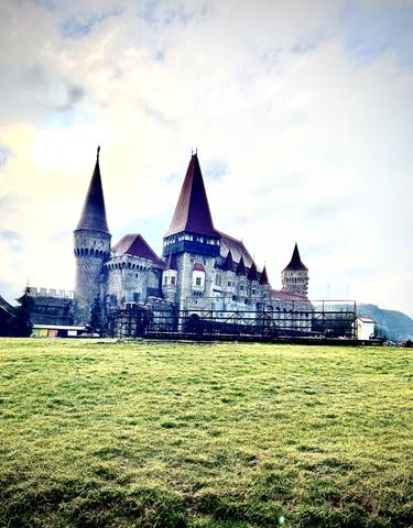 A grand medieval castle with towers and green lawns.