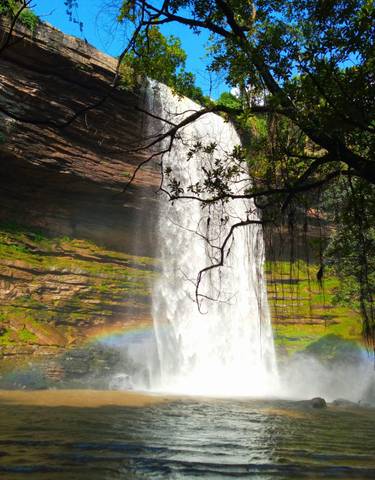 Waterfall cascading over a cliff with a rainbow visible.