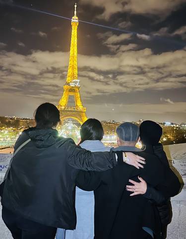 Four people viewing the Eiffel Tower lit up at night.