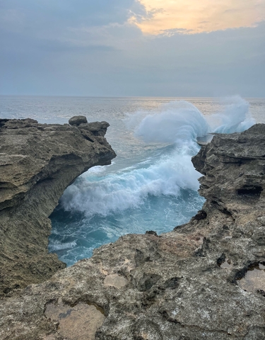 Dramatic ocean waves crashing against rocky cliffs.