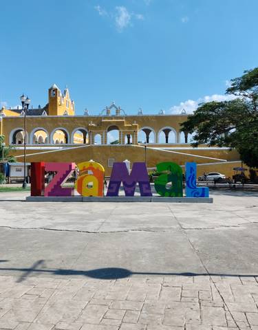Izamal sign with yellow church in the background.
