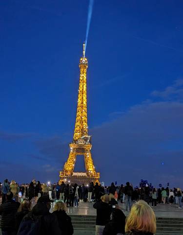 Eiffel Tower illuminated at dusk against a blue sky.