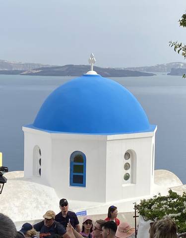 Close-up of a blue-domed church with a sea view.