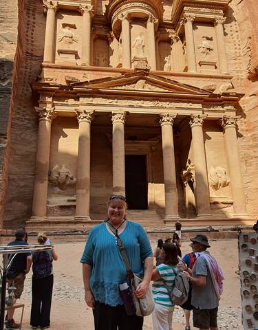 A woman standing in front of the Petra Treasury with carved stone façade.